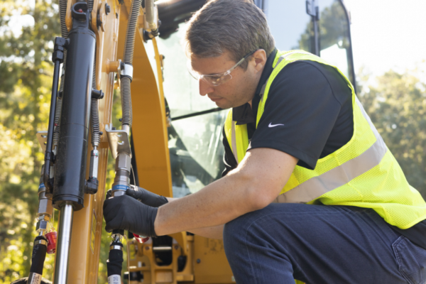 A heavy equipment specialist repairing hydraulic equipment